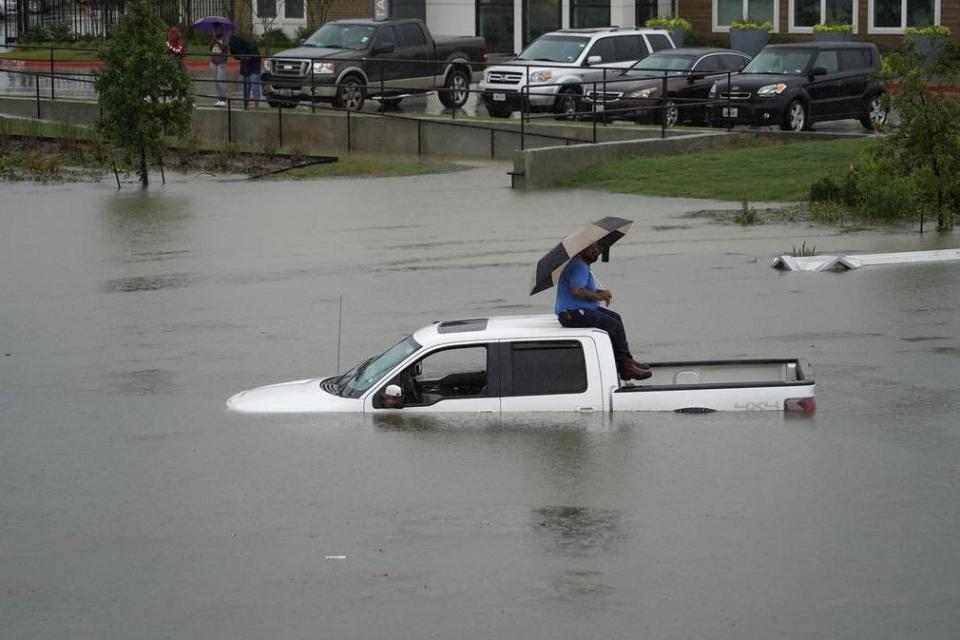 Flash flood: A man sits on top of a truck on a flooded road in Houston on Thursday (AP)