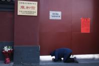 A man prays in front of the closed gate of Lama Temple where a notice saying that the temple is closed for safety concerns following the outbreak of a new coronavirus is seen, in Beijing