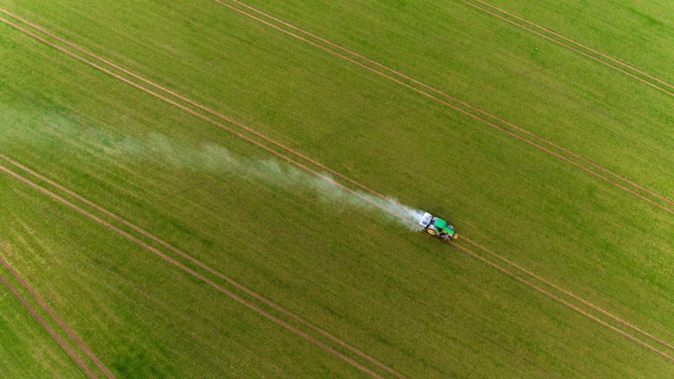 Ein Traktor fährt bei Gammelin über einen Acker und verteilt mit einem Streuer Pflanzendünger.