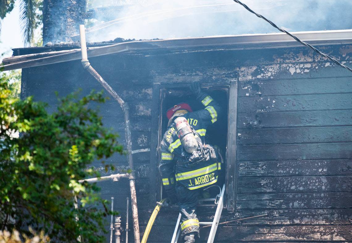 A Sacramento firefighter climbs into the window of a burned apartment building on T Street in Sacramento on Friday, July 12, 2024.