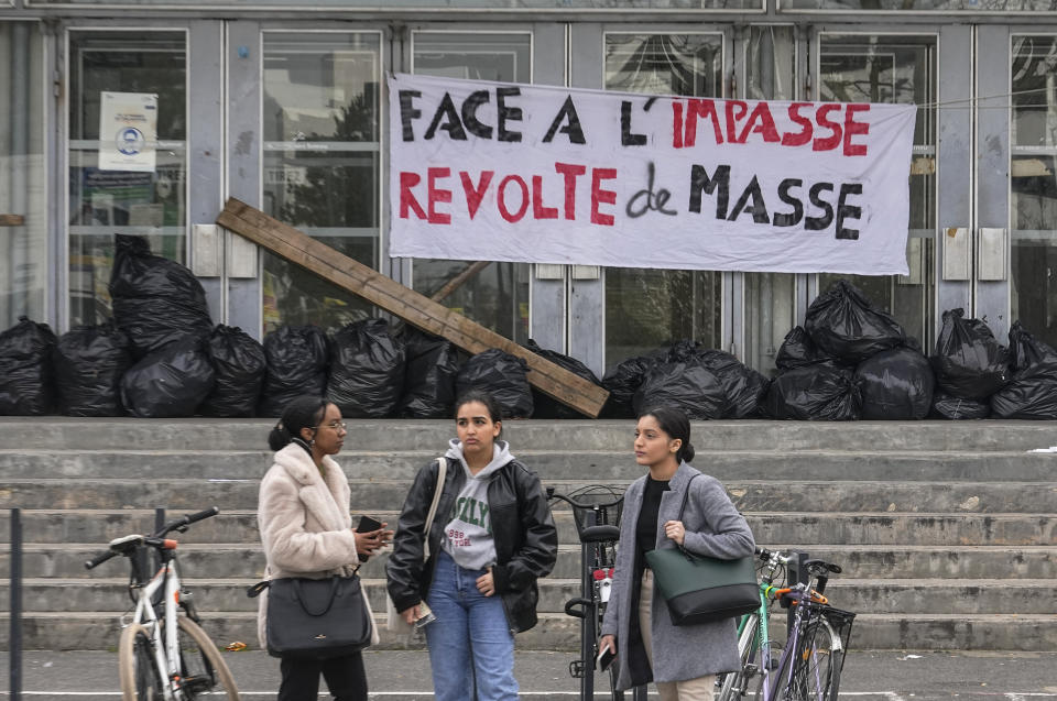 Students gather outside of the blocked university of Nanterre, outside Paris, Friday, march 17, 2023. Students blocked the Nanterre university in protest over President Macron's decision to force through a highly unpopular bill raising the retirement age from 62 to 64 without a vote. Banner reads, "facing the deadlock mass revolt". (AP Photo/Michel Euler)