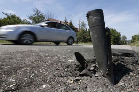 A car drives past the remains of a spent ammunition on the suburbs of Donetsk July 29, 2014. REUTERS/Sergei Karpukhin