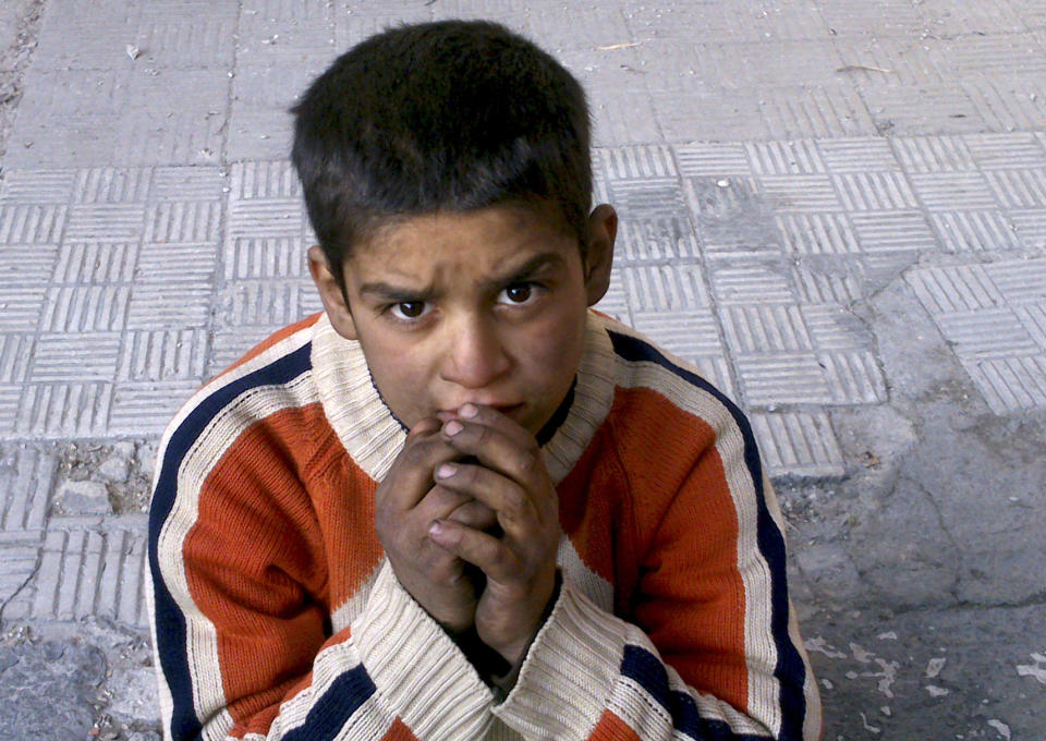 FILE - This Monday, Jan. 6, 2014 activist file photo provided by the group Palestinians of Syria, shows a child sitting on a broken sidewalk after hearing that Syrian authorities would allow civilians to leave in the Palestinian neighborhood of Yarmouk in Damascus, Syria. The chief of the United Nations relief agency supporting Palestinian refugees, Filippo Grandi, said Tuesday he is "deeply disturbed and shaken" by the despair and destruction he'd seen in the besieged Yarmouk refugee camp in the Syrian capital. Many need food and medical treatment immediately, Grandi said in a statement released Tuesday. (AP Photo/Palestinians of Syria, File)