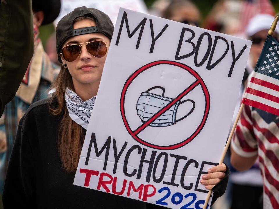 A protester holds up a sign protesting wearing a mask at the Texas State Capital building on April 18, 2020 in Austin, Texas.