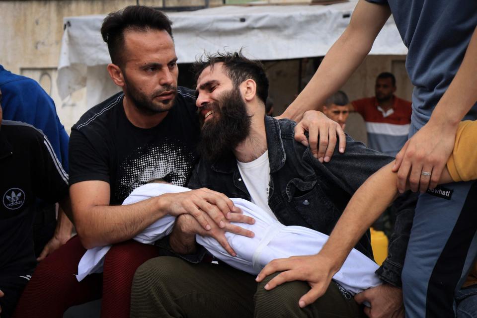 The father of a young boy from the al-Aqad family, reacts as he holds the body of his child (AFP via Getty Images)