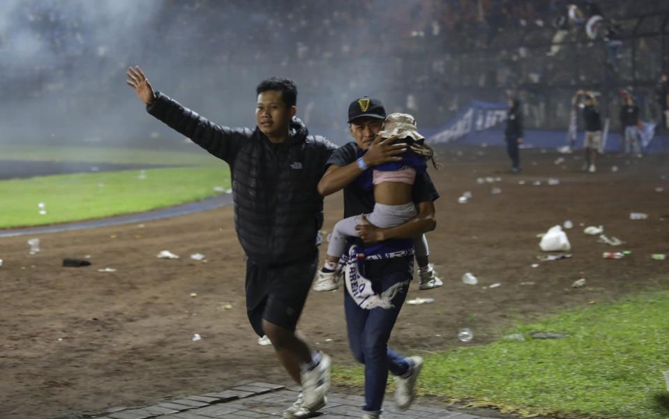 Soccer fans evacuate a girl during a clash between fans at Kanjuruhan Stadium in Malang, East Java, Indonesia - H PRABOW/EPA-EFE/Shutterstock