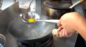 炒飯師傅熟練地先將蛋打入鍋中開始快速翻炒 | At the beginning of the video, the chef skillfully whisked the eggs. (Screenshot taken from <span><a href="https://www.youtube.com/channel/UCH3aos_uf4pGHbkANSbceEg" rel="nofollow noopener" target="_blank" data-ylk="slk:Terry Films;elm:context_link;itc:0;sec:content-canvas" class="link ">Terry Films</a></span> video)