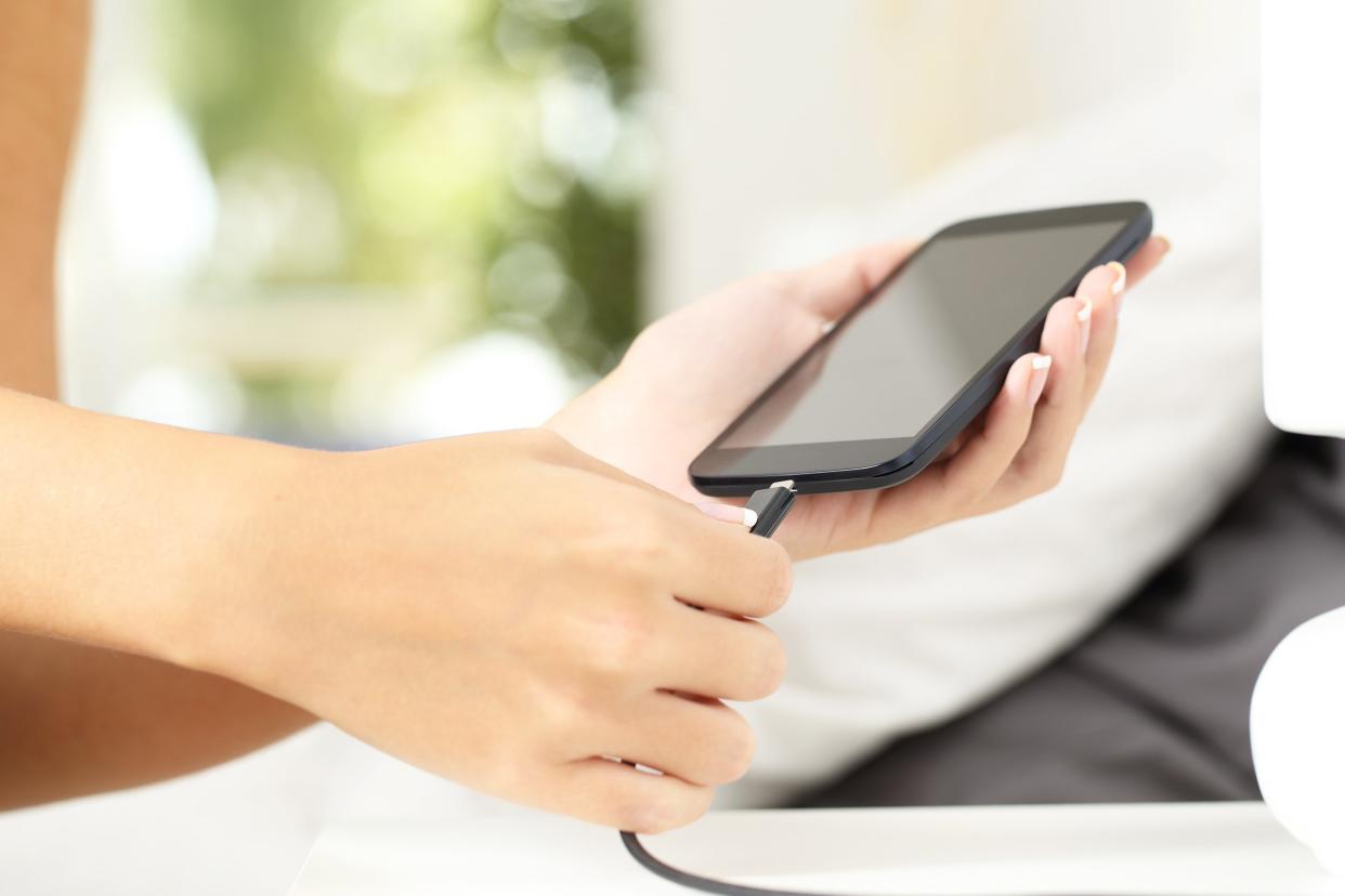 woman hands unplugging a charger in a smart phone in the bedroom at home