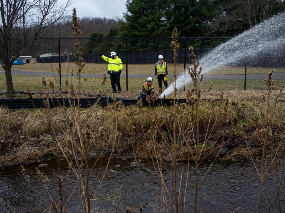A clean-up crew works alongside a stream as clean-up efforts continue on February 16, 2023 in East Palestine, Ohio. On February 3rd, a Norfolk Southern Railways train carrying toxic chemicals derailed causing an environmental disaster.