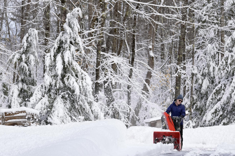 Meghan Hall clears snow from her driveway following a winter storm, Wednesday, March 15, 2023, in Poland, Maine. The storm dumped heavy, wet snow on parts of the Northeast, causing tens of thousands of power outages. (AP Photo/Robert F. Bukaty)