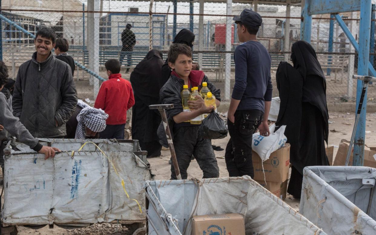 Children collect goods from an aid distribution at a camp for people who lived under ISIS and are now displaced - The Telegraph 