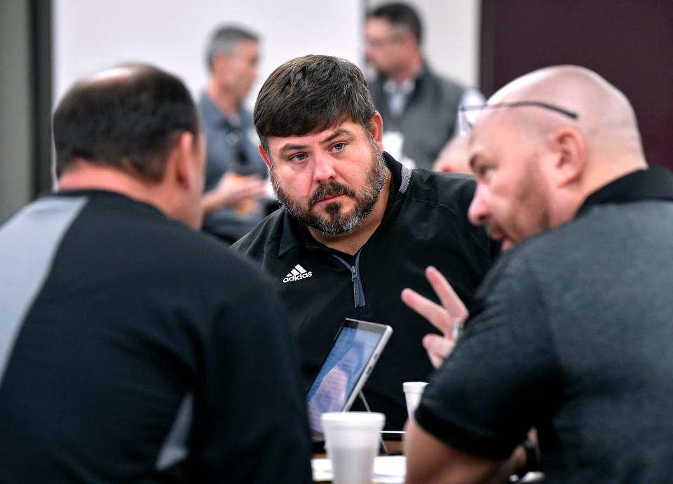 Chad Barron (center), the offensive coordinator at Cross Plains, listens as Head Coach Daniel Purvis (right) offers his strategy to him and defensive coordinator Jared Sanderson during Thursday's UIL Realignment gathering in Abilene.