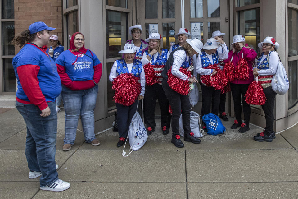 Tyler Pudleiner, left, a teen who was among those injured in a parade last year in Waukesha, Wis., stands with members of the Milwaukee Dancing Grannies before a Veterans’ Day parade in Milwaukee on Saturday, Nov. 5, 2022. The Grannies, who lost three members at that same Christmas parade, invited Pudleiner to help carry their banner. The driver of an SUV sped onto the Waukesha parade route Nov. 21, 2021, and hit and killed six people and injured more than 60 others. “I’ve said it from day one, that we're stronger than him. And in moments like this when we come together, we're showing it,” Pudleiner said. (AP Photo/Kenny Yoo)