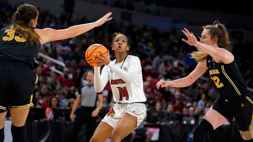 Louisville guard Kianna Smith (14) drives between Michigan forward Emily Kiser (33) and Michigan guard Leigha Brown (32) during the first half of a college basketball game in the Elite 8 round of the NCAA women's tournament Monday, March 28, 2022, in Wichita, Kan.