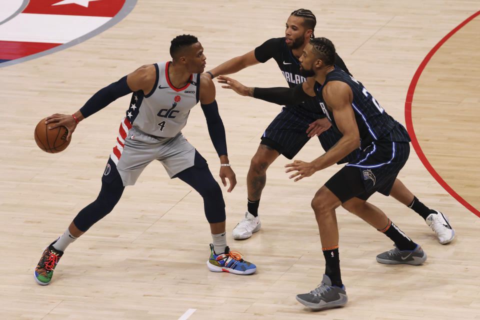 Washington Wizards guard Russell Westbrook (4) holds the ball as Orlando Magic guard Michael Carter-Williams (7) and center Khem Birch (24) defend in the second quarter of an NBA basketball game Saturday, Dec. 26, 2020, in Washington. (Geoff Burke/Pool Photo via AP)