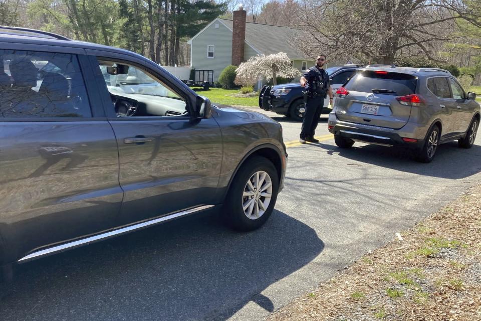 Vehicles move through a police blockade on a road in North Dighton, Mass., Thursday, April 13, 2023. The FBI wants to question a 21-year-old member of the Massachusetts Air National Guard in connection with the disclosure of highly classified military documents on the Ukraine war, two people familiar with the investigation said. (AP Photo/Michelle R. Smith)