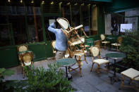 A cafe employee carries chairs as he setting up a terrace, in Paris, Tuesday, June 2, 2020. Parisians who have been cooped up for months with take-out food and coffee will be able to savor their steaks tartare in the fresh air and cobbled streets of the City of Light once more -- albeit in smaller numbers. (AP Photo/Thibault Camus)