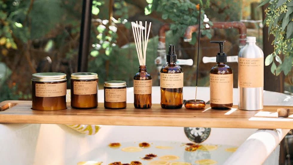 a bathtub tray with bottles and candles on it