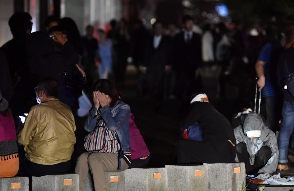 A woman covers her face as she takes shelter on a road following a strong earthquake in Sapporo, northern Japan early Thursday, Sept. 6, 2018. (Yu Nakajima/Kyodo News via AP)