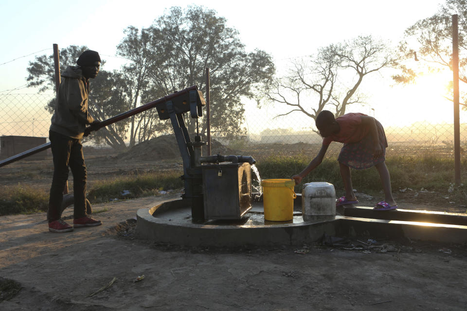 A girl fetches water from a borehole in Harare, Thursday, Aug, 8, 2019. The sight of Harare residents walking home at dask carrying firewood and water buckets has become common as the country struggles with water and power crisis, the worst in over a decade.(AP Photo/Tsvangirayi Mukwazhi)