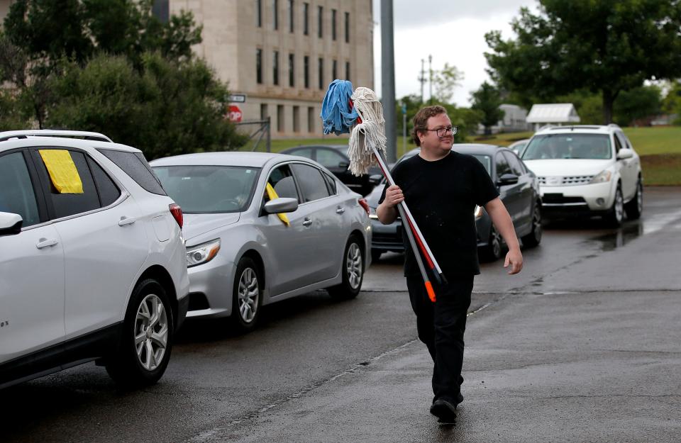 John Swoboda hands our mops to people during a rally by Clean-Up Oklahoma on Wednesday at the state Capitol.