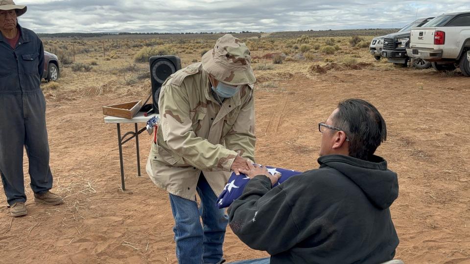 A flag honoring the late Toledo Ross Begay is handed to his son, Randy Ross Begay, at a special Veterans Day event near Crystal, N.M., Nov. 10, 2023.