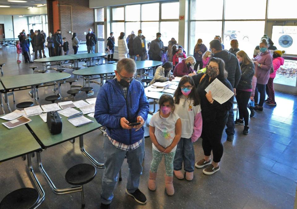 A long line snakes through the Weymouth High School cafeteria as children wait for the COVID-19 vaccine with their parents during a vaccination clinic on Saturday, Nov. 20, 2021.