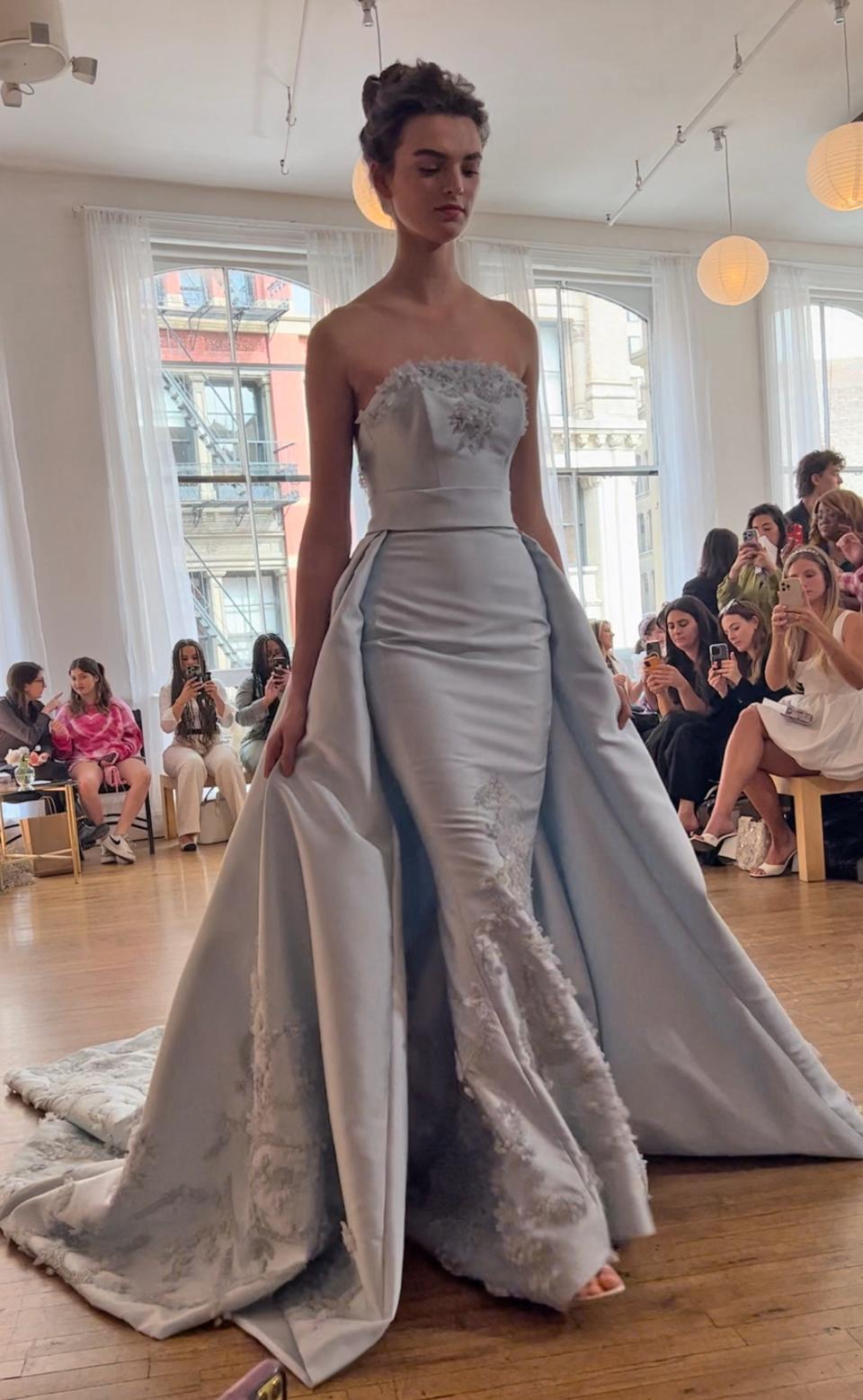 A woman poses in a blue wedding dress with a side train.