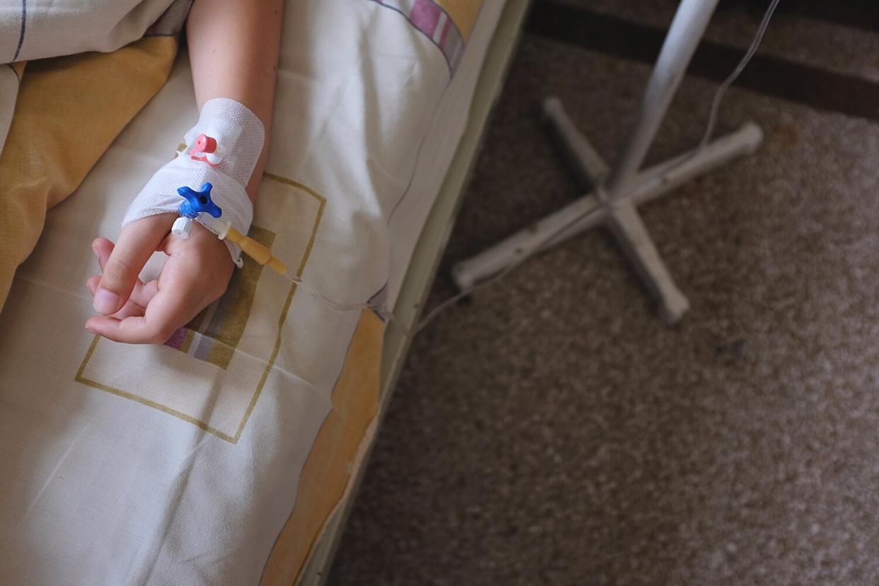 Child's hand in hospital bed, with IV drip attached