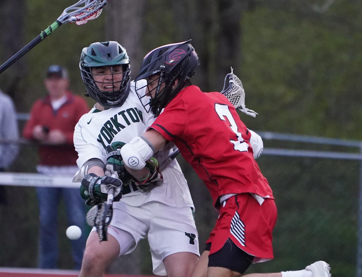 Yorktown's Gianluca Marchini (12) works a shot around Rye's Chase Pepper (3) during their 9-8 double overtime win in boys lacrosse at Yorktown High School in Yorktown Heights. Tuesday, April 30, 2024.