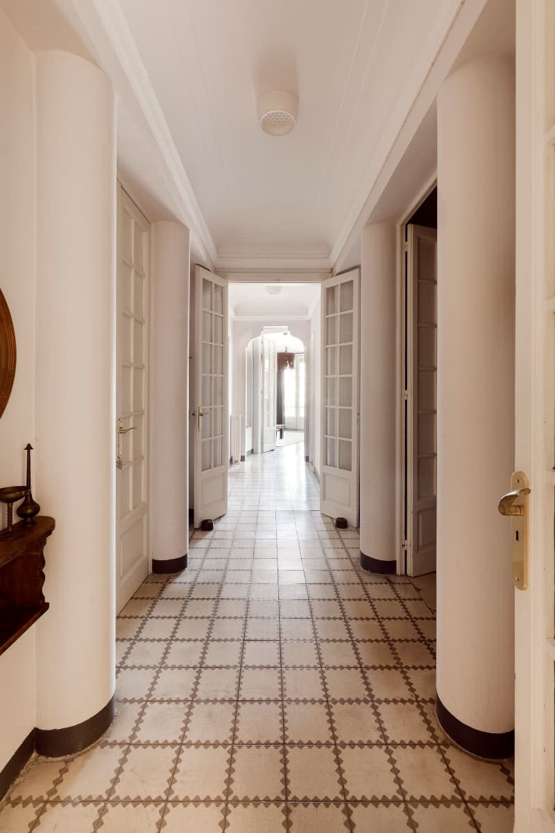 Decorative square tile lines floor of neutral toned hallway.