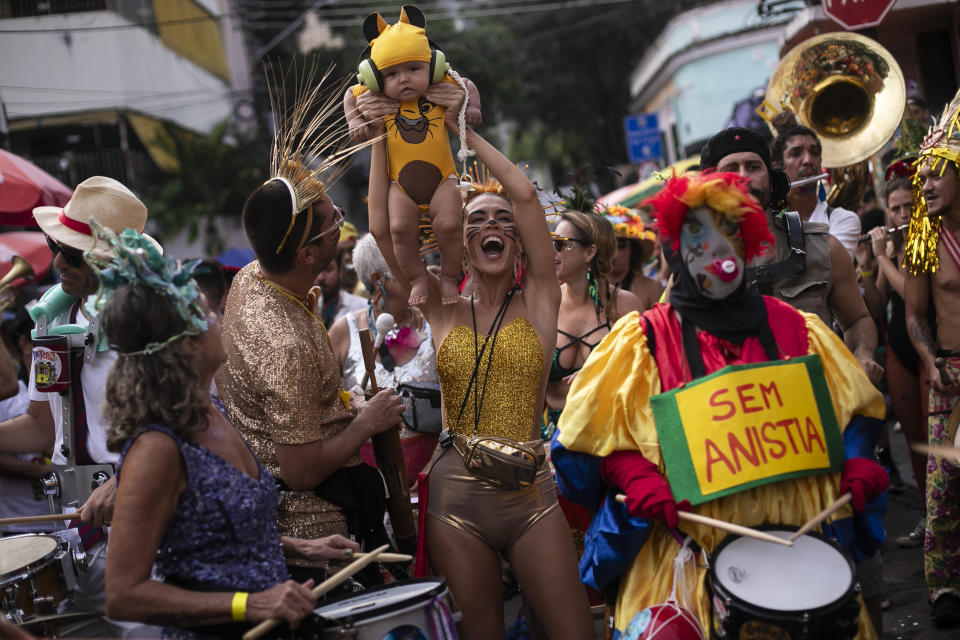 Una mujer muestra a su bebé vestido como Simba, de El rey león, durante la fiesta callejera previa al Carnaval "Cielo en la Tierra", en Río de Janeiro, Brasil, el sábado 3 de febrero de 2024. (AP Foto/Bruna Prado)