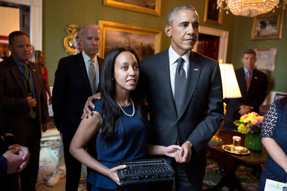 Haben Girma is led through the White House by former President Obama in 2015 holding her Braille computer, an accessibility tool. 