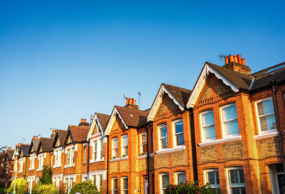 A long row of traditional Victorian terraced houses in Ealing, West London, below a clear blue summer sky.