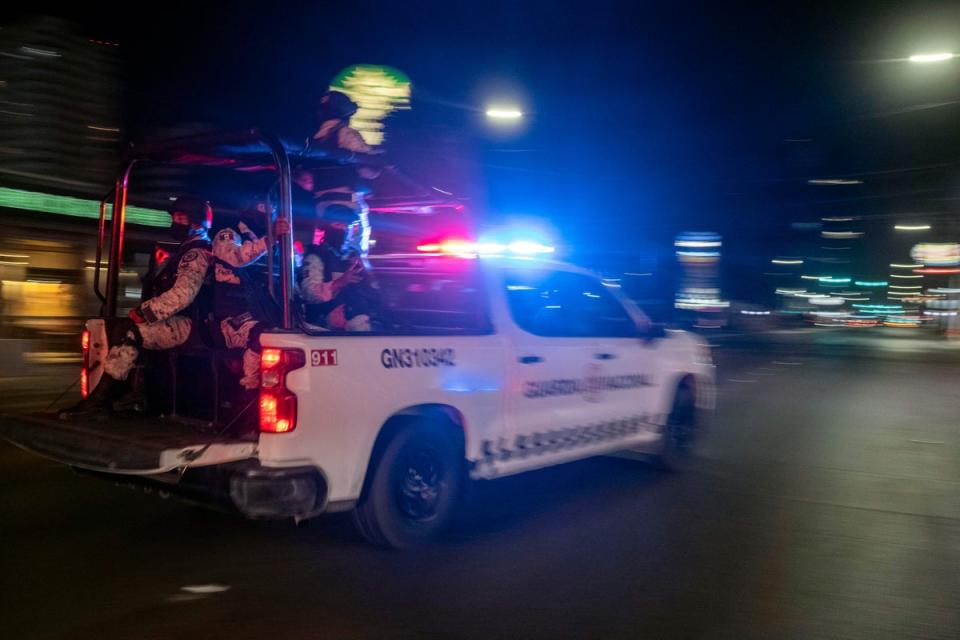 Miembros armados de la Guardia Nacional pasan por delante del lugar donde se encuentra un vehículo de transporte colectivo quemado tras ser incendiado por individuos no identificados en Tijuana, estado de Baja California, México, el 12 de agosto de 2022 (AFP vía Getty Images)