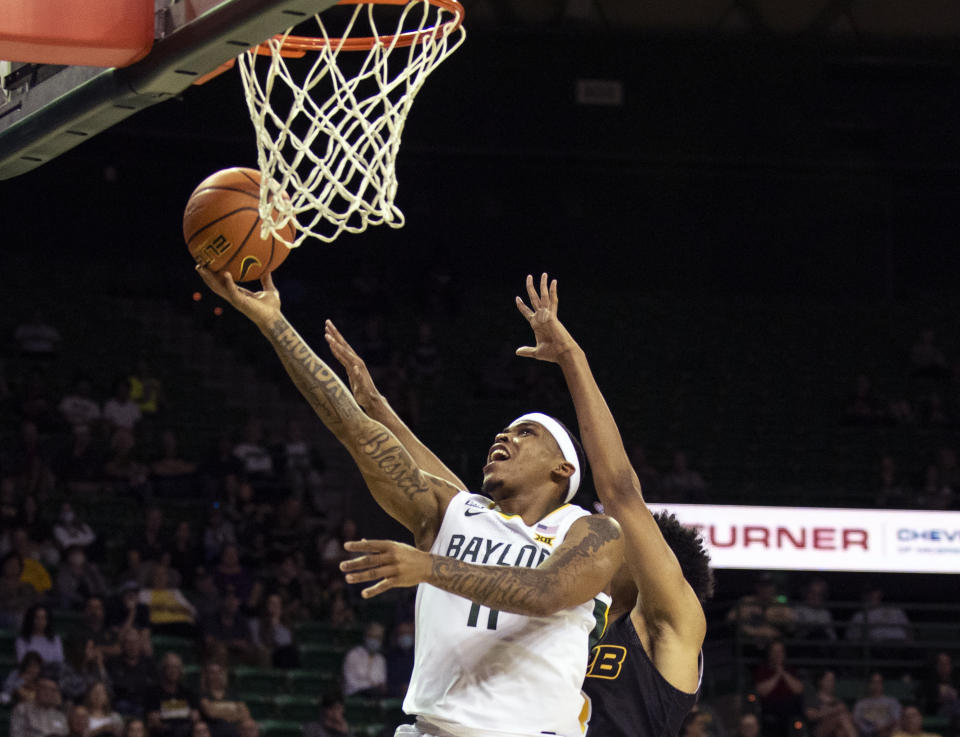 FILE - Baylor's James Akinjo (11) drives past Arkansas-Pine Bluff guard Jaylan Thomas (3) to score in the first half of an NCAA college basketball game in Waco, Texas, Dec. 4, 2021. Reigning national champion No. 4 Baylor added graduate transfer point guard Akinjo from Arizona after the trio of talented and selfless guards All-American Jared Butler, Davion Mitchell and MaCio Teague left for the pros. (AP Photo/Emil Lippe, File)