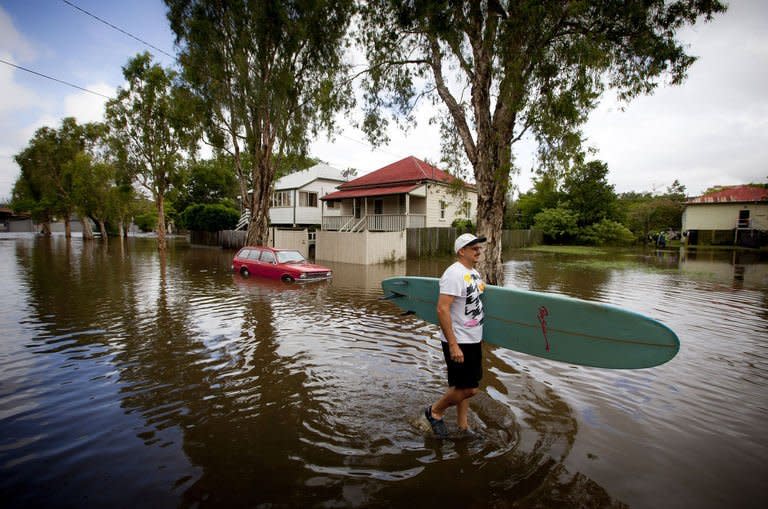 A man rescues a surfboard from a flooded home in the inner Brisbane suburb of Newmarket on January 28, 2013 as high winds and heavy rains brought by ex-tropical cyclone Oswald hit the state of Queensland. The floods have claimed four lives -- the most recent a three-year-old boy killed by a falling tree