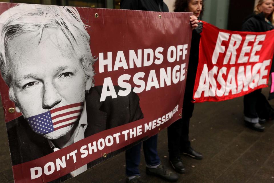 Demonstrators hold banners outside Westminster Magistrates Court in London on Wednesday (AP)