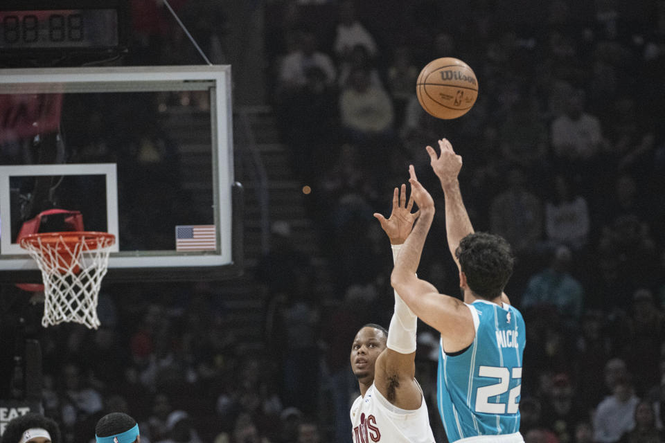 Charlotte Hornets' Vasa Micic (22) shoots over Cleveland Cavaliers' Isaac Okoro, second from right, during the first half of an NBA basketball game in Cleveland, Sunday, April 14, 2024. (AP Photo/Phil Long)