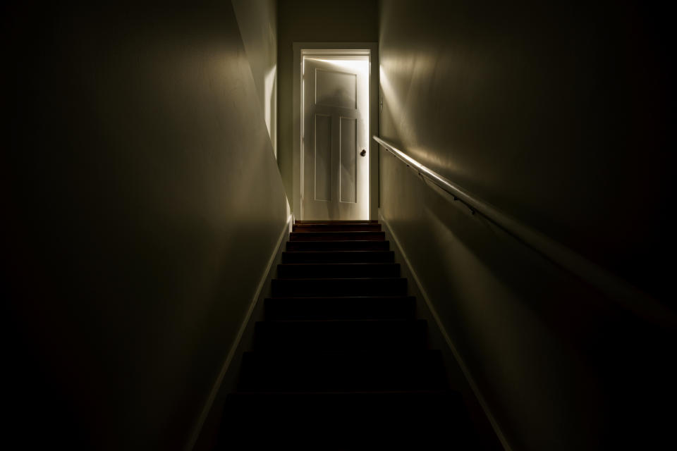 A door ajar at the top of a flight of stairs