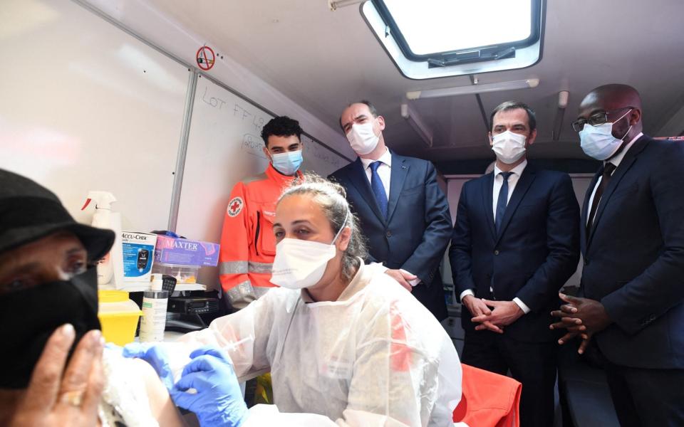 French Health Minister Olivier Veran (2ndR) watches as a woman receives a Pfizer vaccine in Paris - Alain JOCARD / AFP