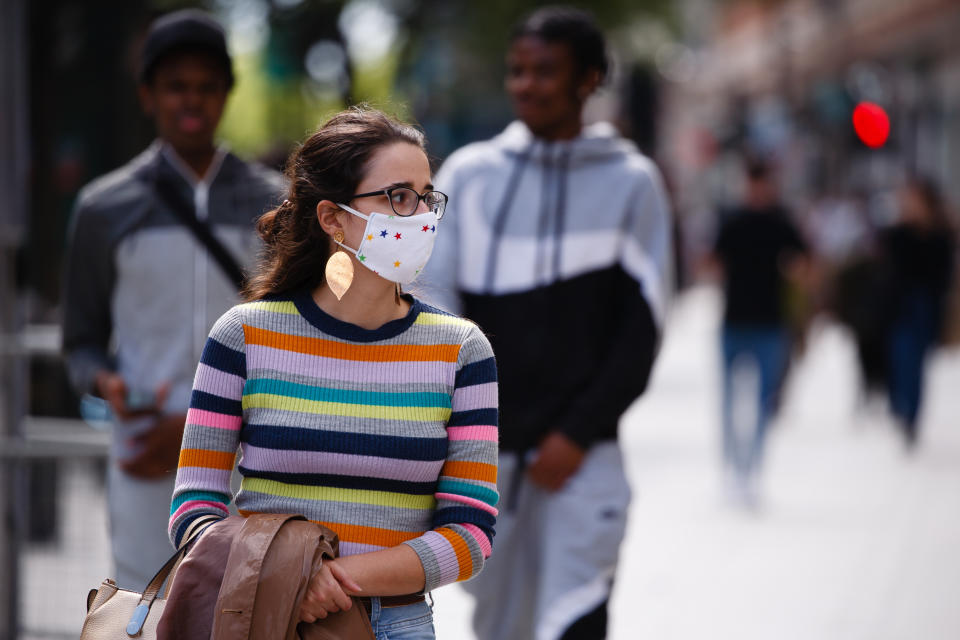 A young woman wearing a face mask waits at a pedestrian crossing on Oxford Street in London, England, on June 20, 2020. Today has been the first Saturday of high street shopping since non-essential retail stores across England were allowed to reopen last week, having been closed under the coronavirus lockdown for nearly three months. Yesterday, monthly retail sales data from the UK's Office for National Statistics (ONS) revealed the beginnings of a rebound during May, with a 12 percent recovery from record falls in April, but sales nonetheless remained 13 percent below February's pre-pandemic total. Retail sales figures for June, taking into account this month's reopening of the sector, will be published by the ONS on July 24. (Photo by David Cliff/NurPhoto via Getty Images)