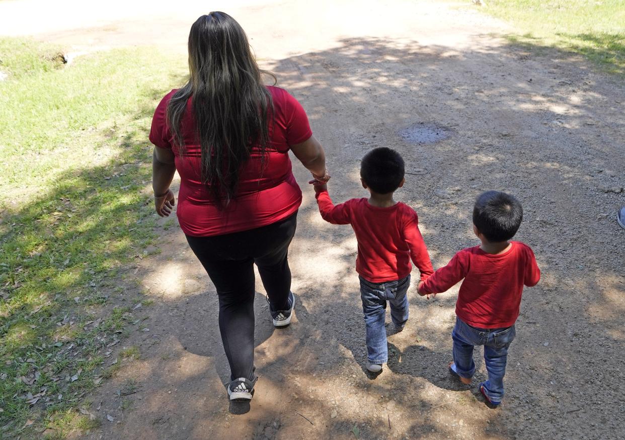 Veronica Pineda, left, walks down the driveway with her twin sons, Nathan & Josue Barcenas, Sunday, April 30, 2023, across the street from the scene of a mass shooting Friday night, in Cleveland, Texas. The search for a Texas man who allegedly shot his neighbors after they asked him to stop firing off rounds in his yard stretched into a second day Sunday, with authorities saying the man could be anywhere by now. Francisco Oropeza, 38, fled after the shooting Friday night that left five people dead, including a young boy. (AP Photo/David J. Phillip)