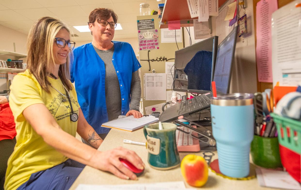 Michelle Boggs, front in yellow, and Anna Antilla look over the schedule for the day at Indiana Health Centers Bedford last month.