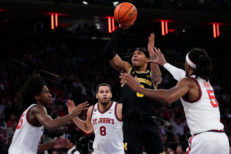 Michigan's Dug McDaniel shoots over St. John's Daniss Jenkins (5) and Chris Ledlum (8) during the first half of an NCAA basketball game, Monday, Nov. 13, 2023, in New York. (AP Photo/Frank Franklin II)