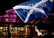 A supporter from the "Yes" Campaign waves a Scottish Saltire flag outside the Scottish Parliament in Edinburgh, Scotland