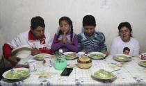 Free Peru party presidential candidate Pedro Castillo, from left, daughter Alondra, son Arnold and wife Lilia Paredes, pray before eating breakfast, in their home in Chugur, Peru, Friday, April 16, 2021. Castillo, a rural teacher, who has proposed rewriting Peru's constitution and deporting all immigrants living in the country illegally who commit crimes, will face rival candidate Keiko Fujimori in the June 6 presidential run-off election. (AP Photo/Martin Mejia)