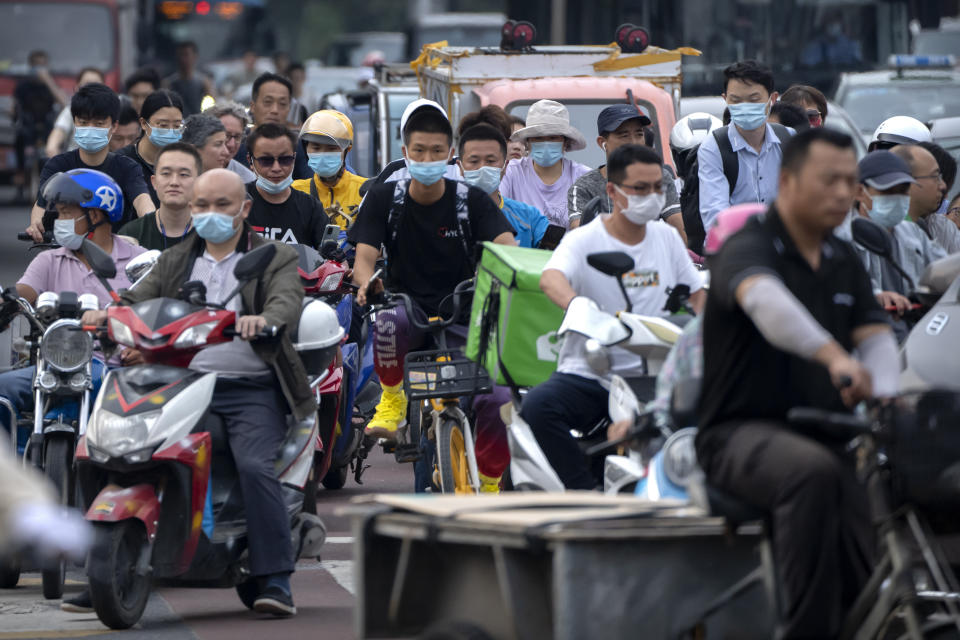 People riding bicycles and scooters wait to cross an intersection during rush hour in Beijing, Friday, July 2, 2021. A small but visible handful of urban Chinese are rattling the ruling Communist Party by choosing to "lie flat," or reject high-status careers, long work hours and expensive cities for a "low-desire life." That clashes with party ambitions to make China a wealthier consumer society. (AP Photo/Mark Schiefelbein)