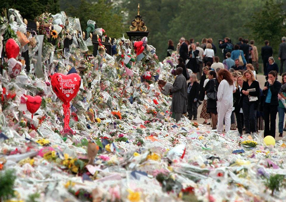 Mourners file past the tributes left in memory of Diana Princess of Wales at Kensington Palace in London, Friday, Sept. 5, 1997. (AP Photo/David Brauchli)