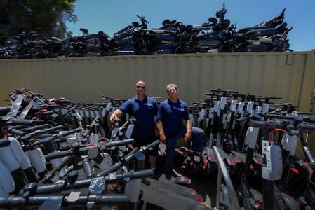 Scoot Scoop founders John Heinkel and Dan Borelli, two professional repo men who have formed a company that acts on behalf of business owners and landlords, pose for a picture amid some of the thousands of scooters they have impounded in San Diego, C